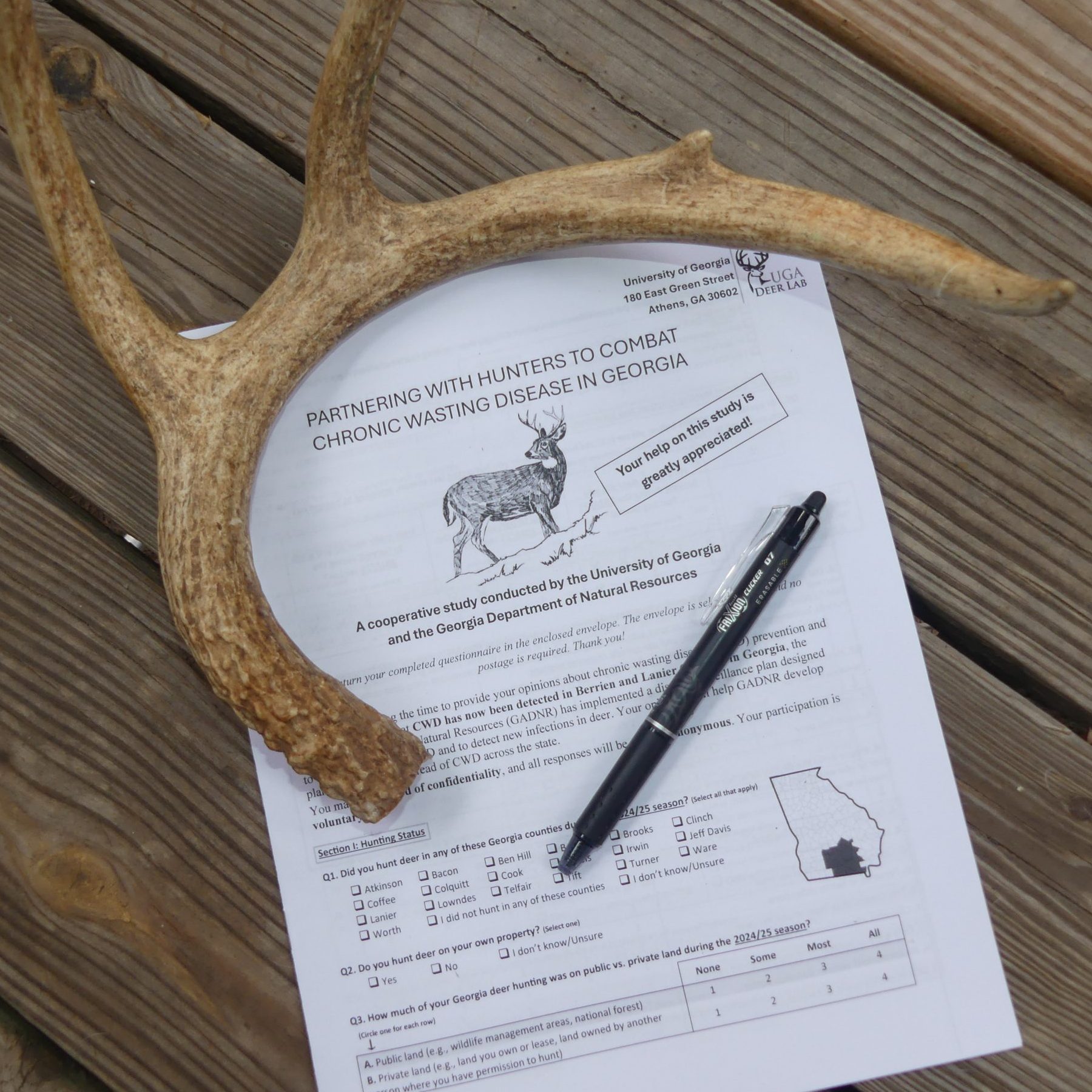 "Partnering with Hunters to Combat Chronic Wasting Disease in Georgia" survey on a picnic table with a deer antler and pen.
