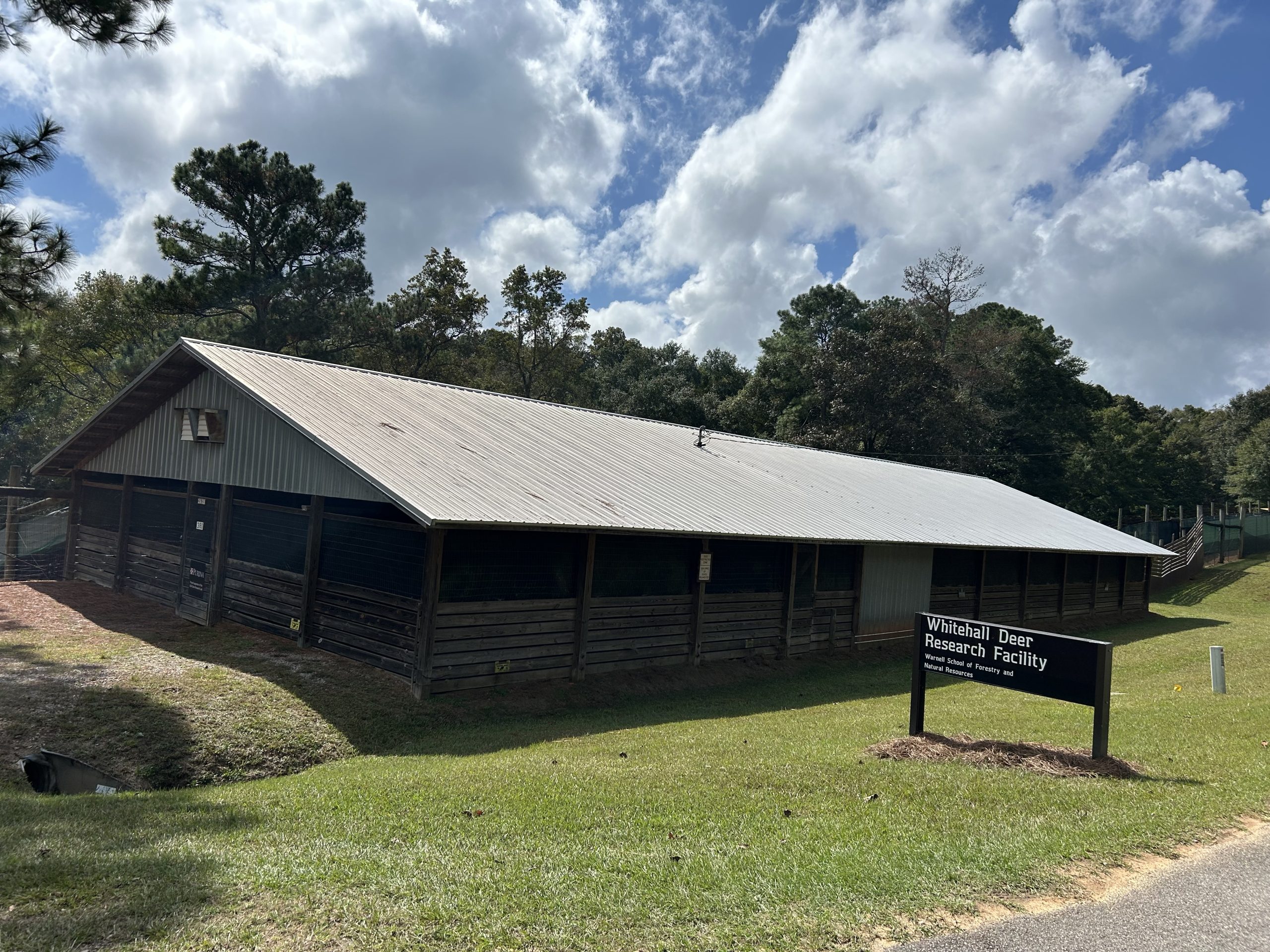 Metal roofed building (Whitehall Deer Research Facility) with shed enclosures for UGA Deer Lab research.