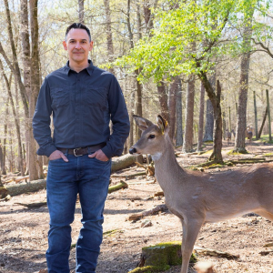 Gino D'Angelo is standing next to a single deer.